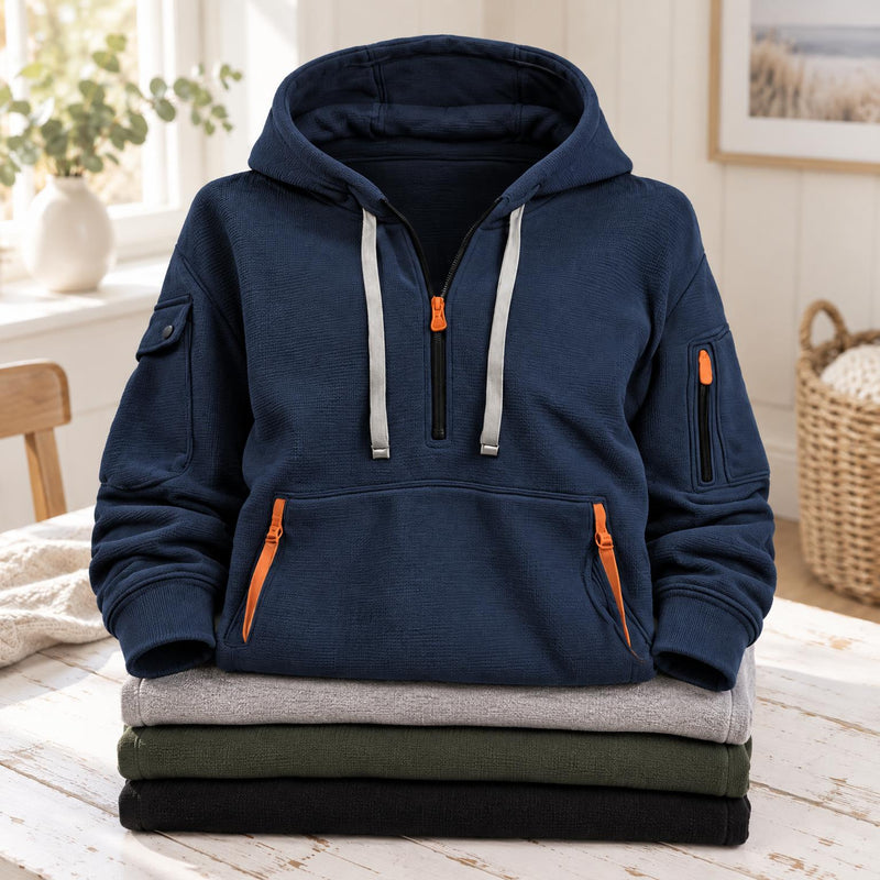 Marineblauwe hoodie met halve rits en kangoeroezak, bovenop een stapel gevouwen truien 2
