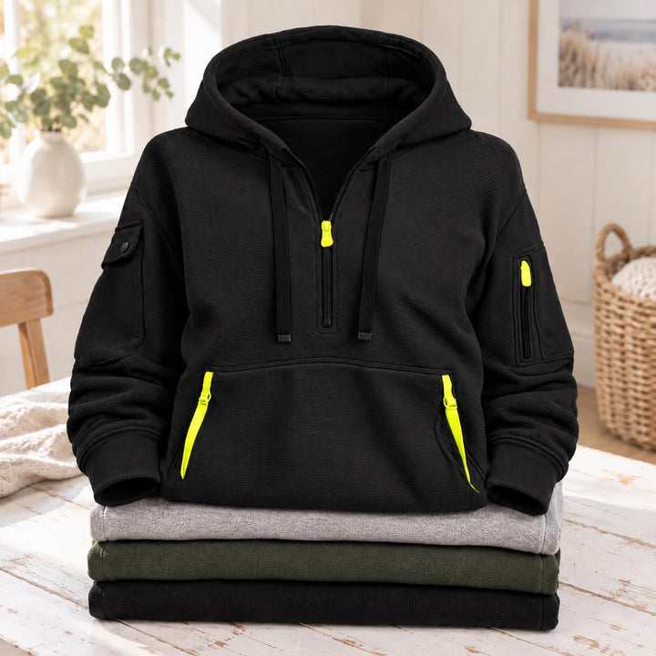 Zwarte hoodie met felgele ritstrekkers op borst, mouw en buikzak, op een stapel 5