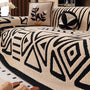Beige bankhoes met zwart geometrisch patroon van driehoeken en ruiten, met bloemenkussen en ronde kussenbal 17