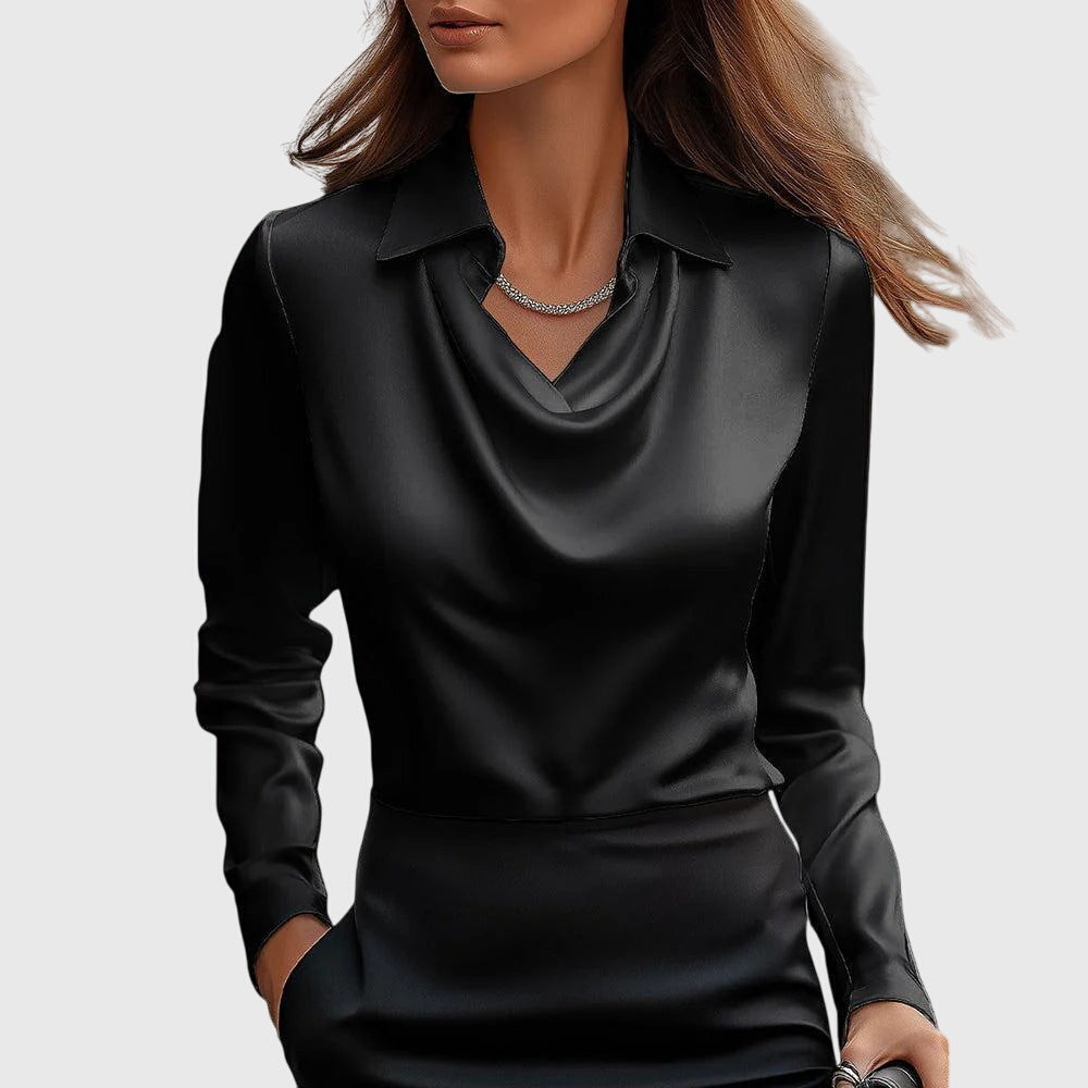 Model draagt de blouse in zwart satijn met gedrapeerde hals en kraag, gecombineerd met een zwarte rok en fijne ketting. 3