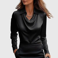 Model draagt de blouse in zwart satijn met gedrapeerde hals en kraag, gecombineerd met een zwarte rok en fijne ketting. 3