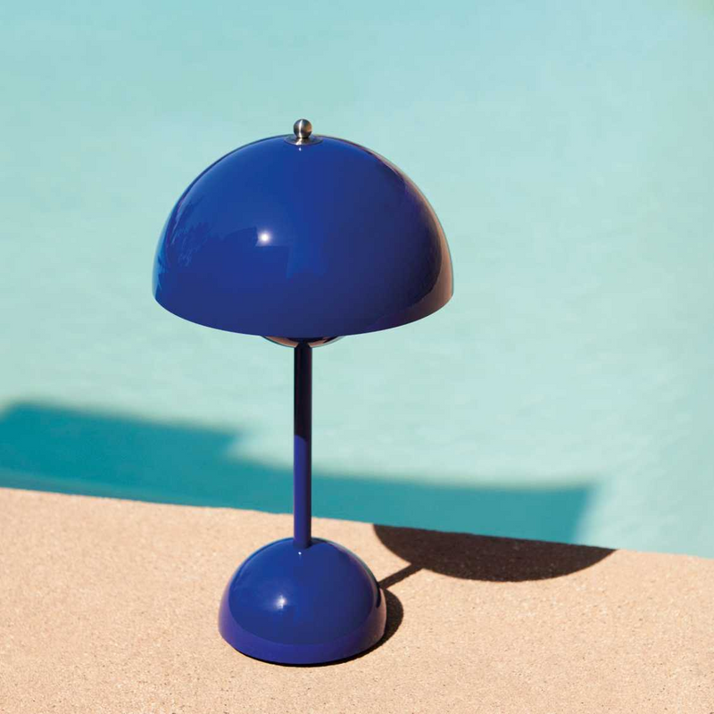 Kobaltblauwe lamp op een zandkleurige rand naast een turquoise zwembad 26