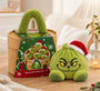Groene knoedelknuffel met kerstmuts en boze blik naast een groene stoommand op een houten tafel 20