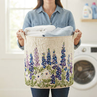 Vrouw in spijkerblouse houdt de mand vast aan de canvas handgrepen, gevuld met handdoeken, voor een wasmachine. 4