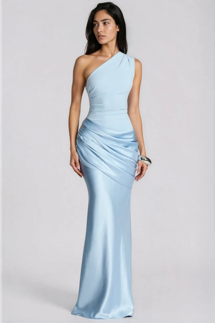 Model in lichtblauwe maxi-jurk met één schouder en gedrapeerde satijnen heup, frontaal in beeld met zilveren armband. 1