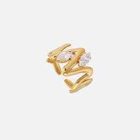 Goudkleurige open ring met golvend, vloeiend ontwerp en twee heldere markiesvormige steentjes, schuin van boven gefotografeerd op een lichte achtergrond. 1
