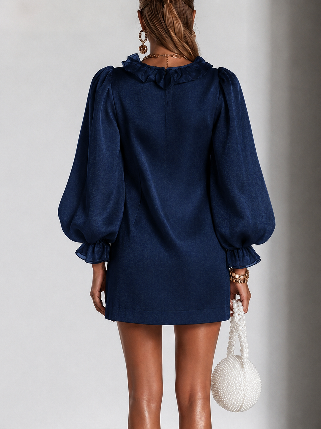 Achterkant van de marineblauwe mini-jurk met ruchesrand om de hals, ritssluiting in de rug en pofmouwen. 7