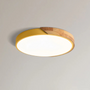 Ronde plafondlamp met gele rand en houten deel, close-up tegen een lichte plafondachtergrond 14