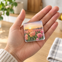 Een hand houdt een kleine vierkante acrylmagneet met een tulpenveld bij zonsondergang vast 6