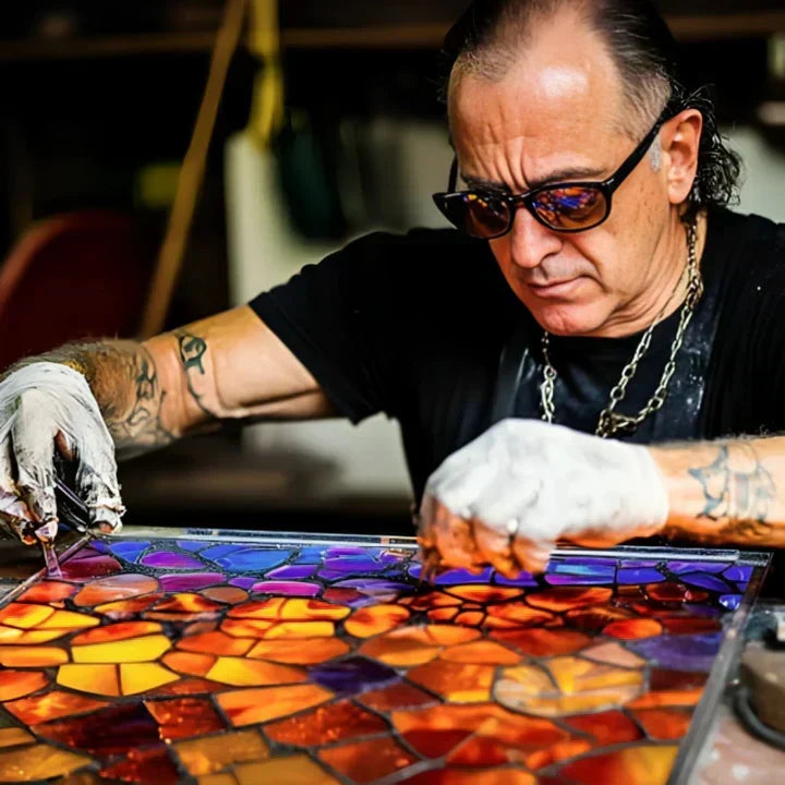 Ambachtsman met tatoeages legt met handschoenen kleurrijke glasstukjes in een mozaïek, bezig met het maken van het lampje 2