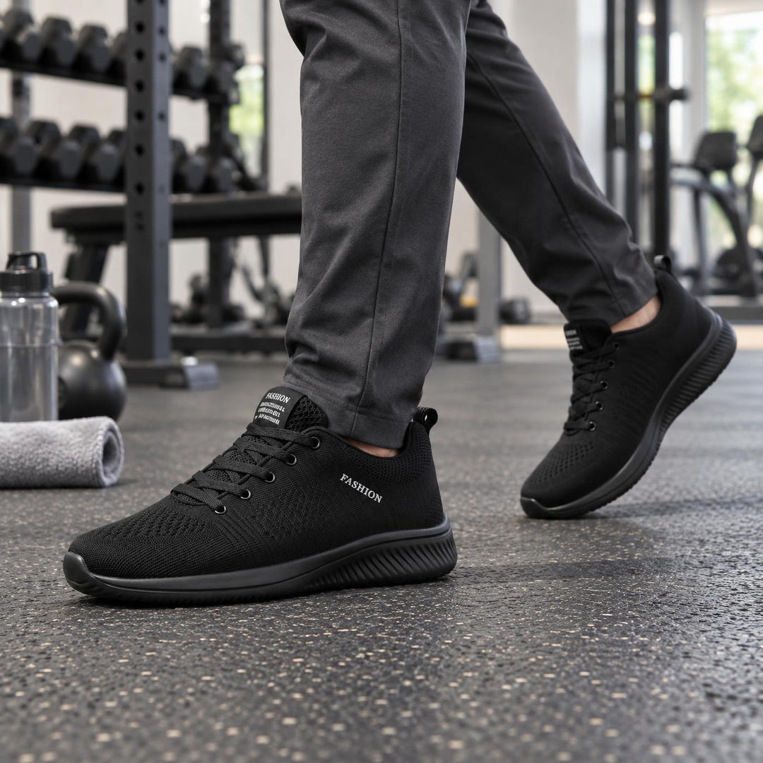 Heer loopt in de sportschool met geheel zwarte gebreide sneakers en een grijze broek 1