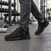 Heer loopt in de sportschool met geheel zwarte gebreide sneakers en een grijze broek 1