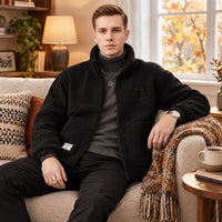Man in zwart teddyfleece vest over grijze coltrui, zittend op een bank in een herfstsfeer 1