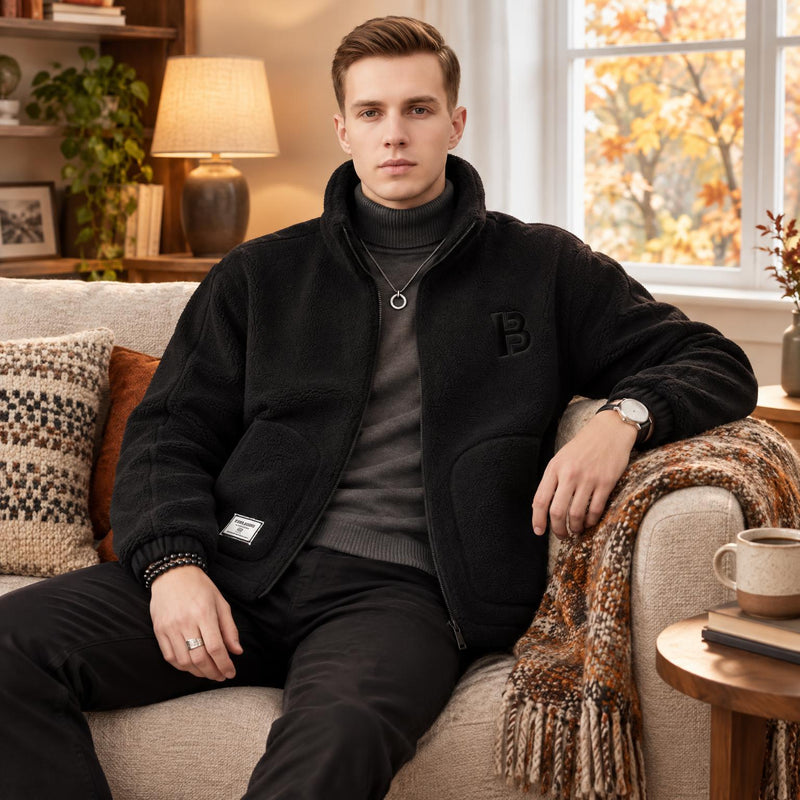 Man in zwart teddyfleece vest over grijze coltrui, zittend op een bank in een herfstsfeer 1