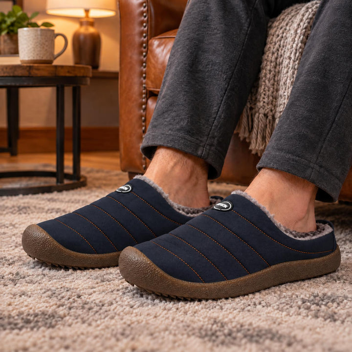 Donkerblauwe gewatteerde pantoffels met pluizige voering, gedragen op een beige tapijt bij een leren stoel 3