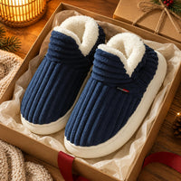 Marineblauwe geribbelde pantoffels met witte pluche rand in een cadeaudoos met vloeipapier, kerstsfeer eromheen 1