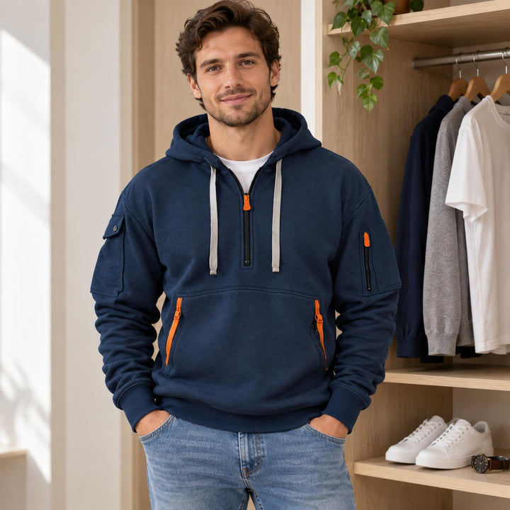 Gevouwen marineblauwe hoodie op een houten plank, naast een horloge en witte sneakers 1