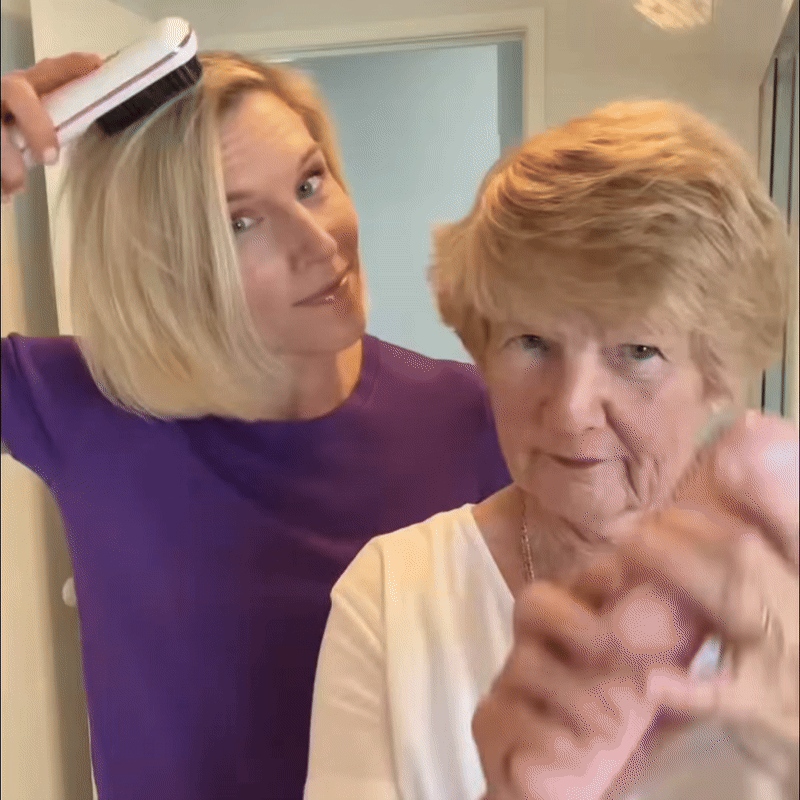 Vrouw in paars shirt borstelt haar blonde bob met een witte stylingborstel naast een oudere vrouw met kort haar. 9