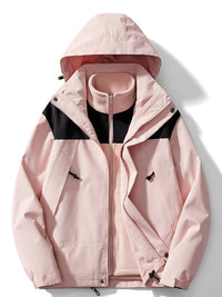Roze outdoorjas met zwarte schouderpanelen en capuchon, geopend met de roze fleecevoering en opstaande kraag zichtbaar. 6