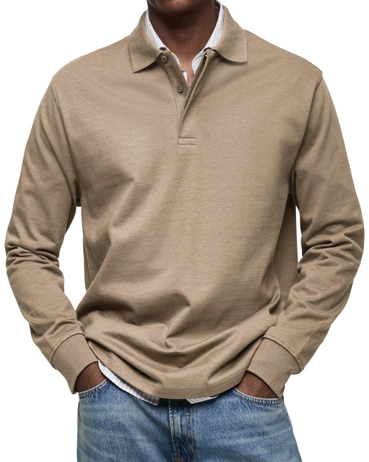 Man draagt het poloshirt met lange mouwen in beigebruin, met handen in de zakken van een spijkerbroek. 8