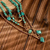 Close-up van de turquoise kralen, steenhangers en gouden kettingen op een houten ondergrond 4