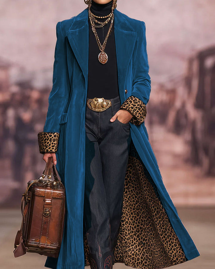 Dezelfde jas in blauw fluweel op een catwalk, open gedragen met luipaardmanchetten, luipaardvoering, spijkerbroek en bruine leren tas. 6