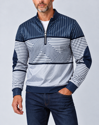 Man met grijze baard draagt de marineblauw-witte gestreepte pullover met halve ritssluiting, een witte trui eronder en een donkere spijkerbroek, voorkant. 1