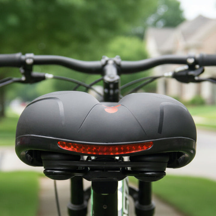 Achteraanzicht van het zwarte zadel op een fiets met een rode reflecterende strip, voor een rustige straat. 2