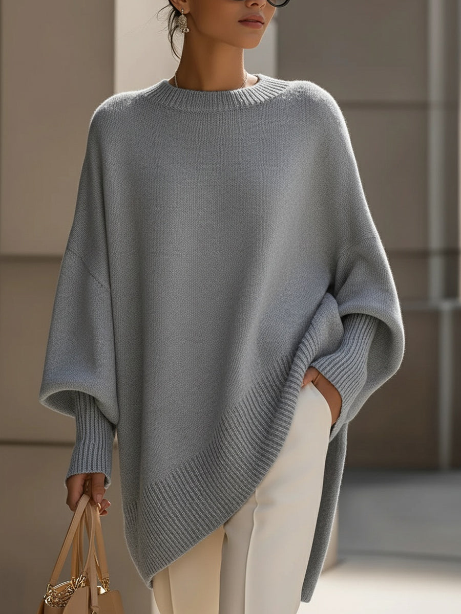 Grijze gebreide poncho gedragen met witte broek, hand in de zak en beige tas 10