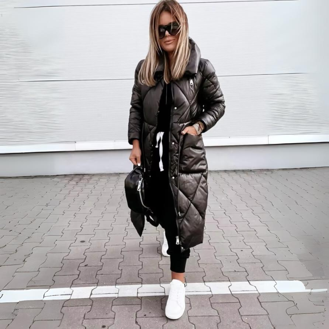Vrouw loopt in de zwarte lange jas met handen in de zakken, op straat gecombineerd met zwarte broek en witte sneakers. 5