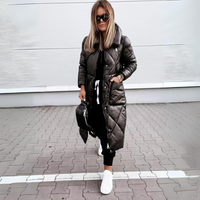 Vrouw loopt in de zwarte lange jas met handen in de zakken, op straat gecombineerd met zwarte broek en witte sneakers. 5