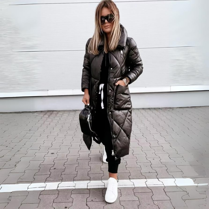 Vrouw loopt in de zwarte lange jas met handen in de zakken, op straat gecombineerd met zwarte broek en witte sneakers. 5