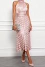 Model draagt de halsjurk in oudroze met een grijsgroene clutch en roze pumps, rok versierd met ronde schijfjes. 3