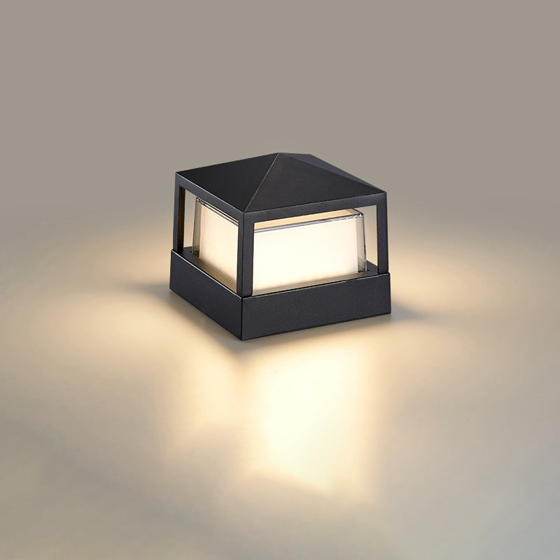 Vierkante zwarte lamp met piramidevormig dak en warm licht op een neutrale achtergrond. 10