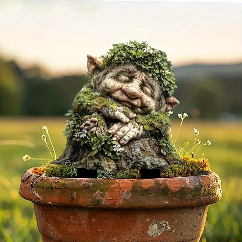 Tuinprikker van de slapende trol in een terracotta pot, met een grassige heuvel bij zonsondergang op de achtergrond. 17