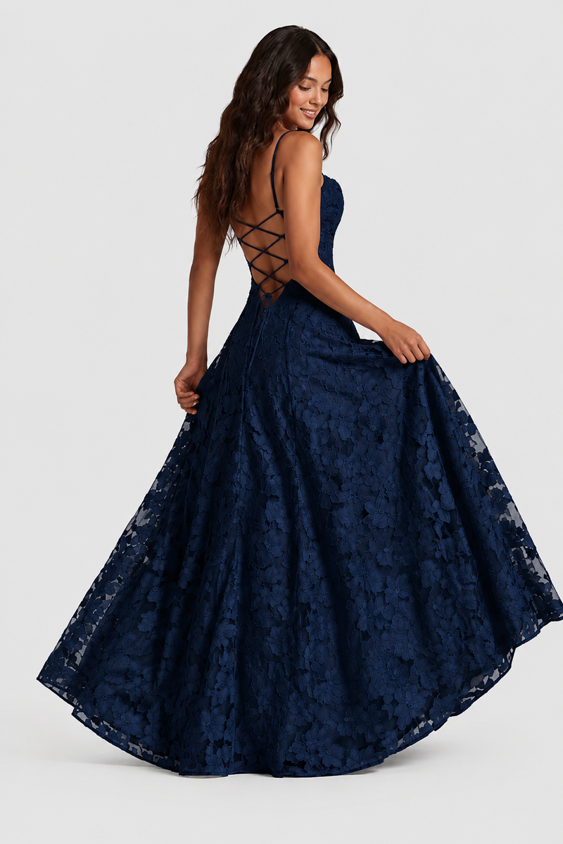 Model in marineblauwe jurk toont de open rug met gekruiste veters terwijl ze de wijde kanten rok vasthoudt. 5
