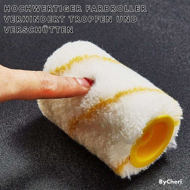 Losse witte verfroller met gele strepen en gele kern op een donkere ondergrond, met een vinger die de zachte pluche indrukt. 7