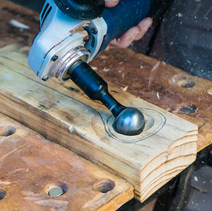 Haakse slijper met bolfrees holt een plank uit langs een getekende omtrek, houtsnippers vliegen weg 2