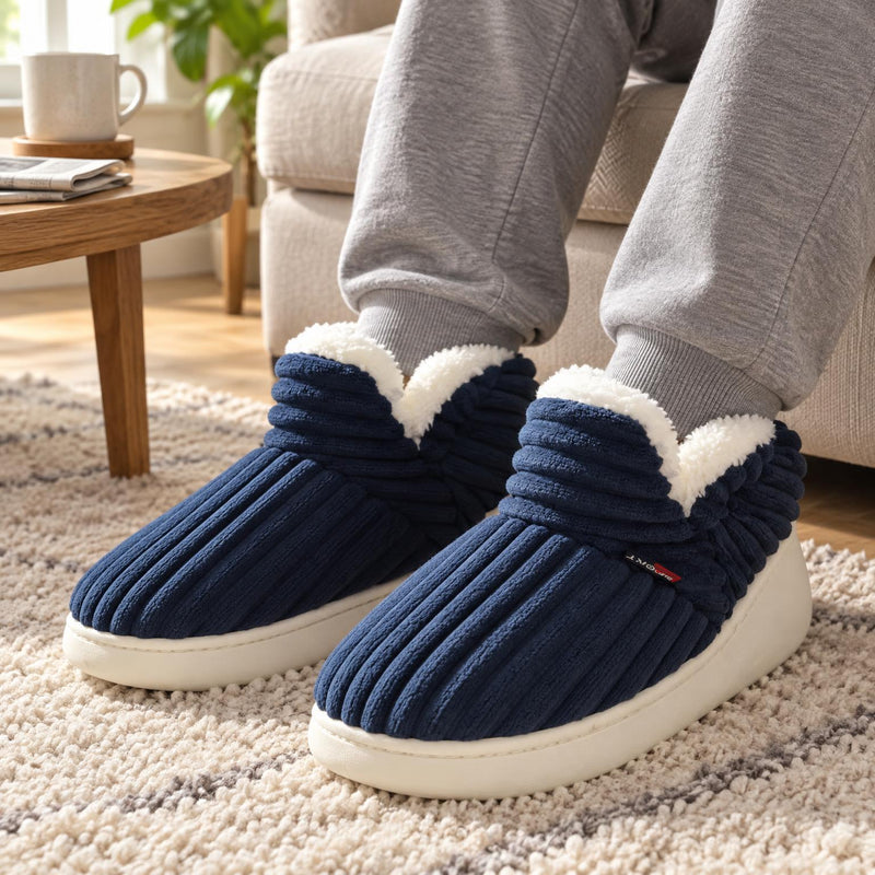 Marineblauwe geribbelde pantoffels met witte pluche rand, gedragen door een man op de bank bij een salontafel 1