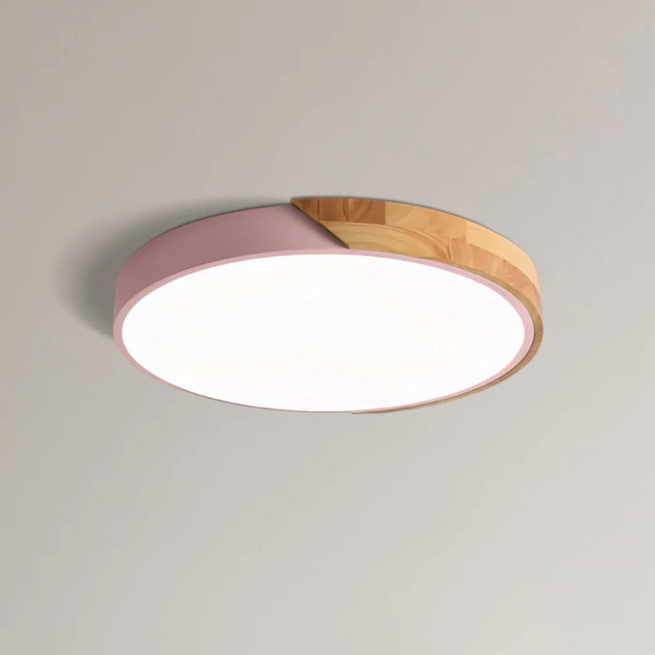 Ronde plafondlamp met roze rand en houten deel, close-up tegen een lichte plafondachtergrond 11