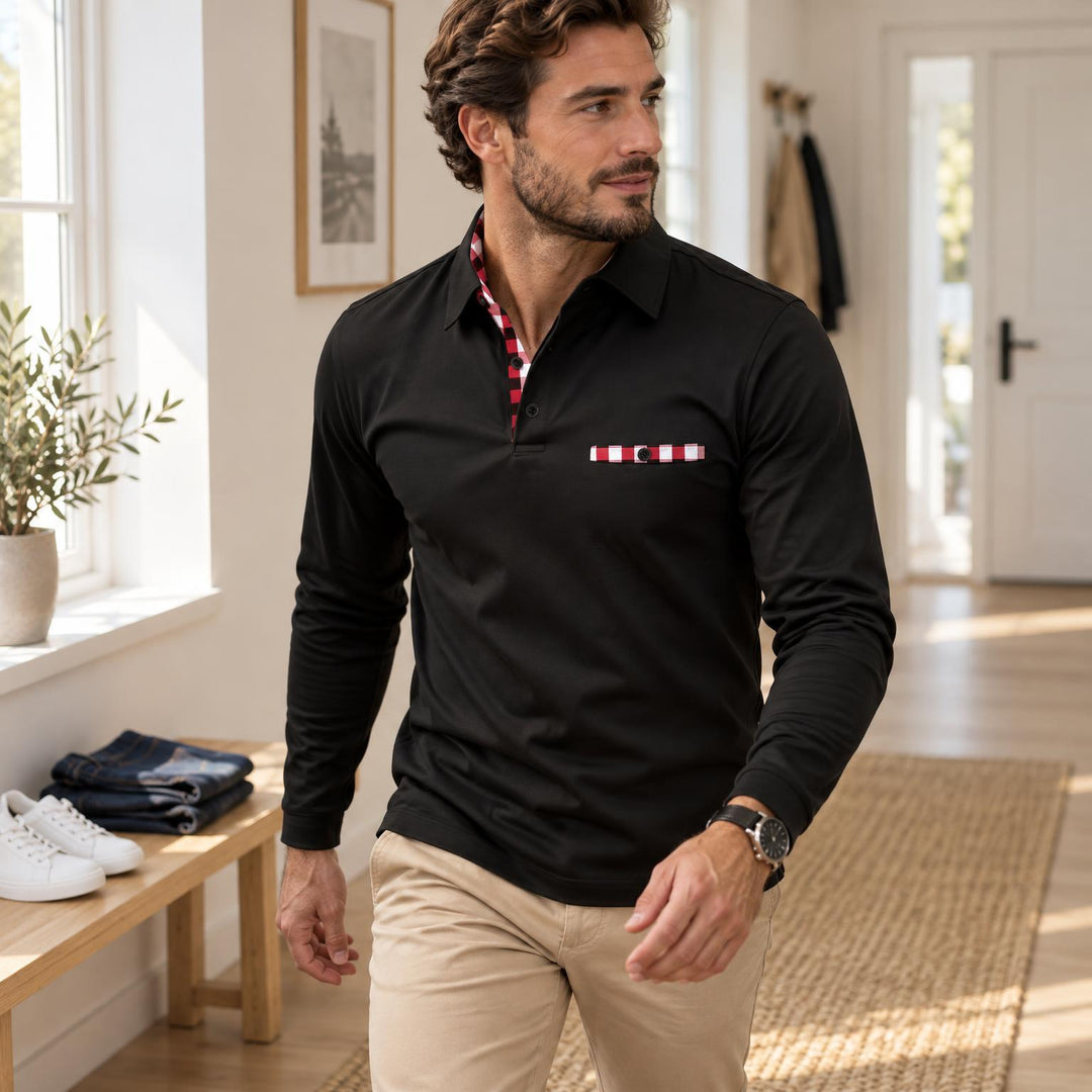 Man draagt zwarte polo met lange mouwen en rood-wit geruite details, in een lichte hal 1