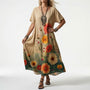 Model draagt de beige jurk met grote oranje en rode bloemen aan de onderkant die overlopen in groen, met zwarte bandjessandalen. 3
