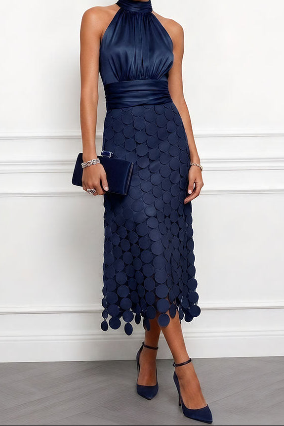 Model draagt de halsjurk in donkerblauw met een fluwelen clutch en marineblauwe pumps, rok met grote ronde applicaties. 4
