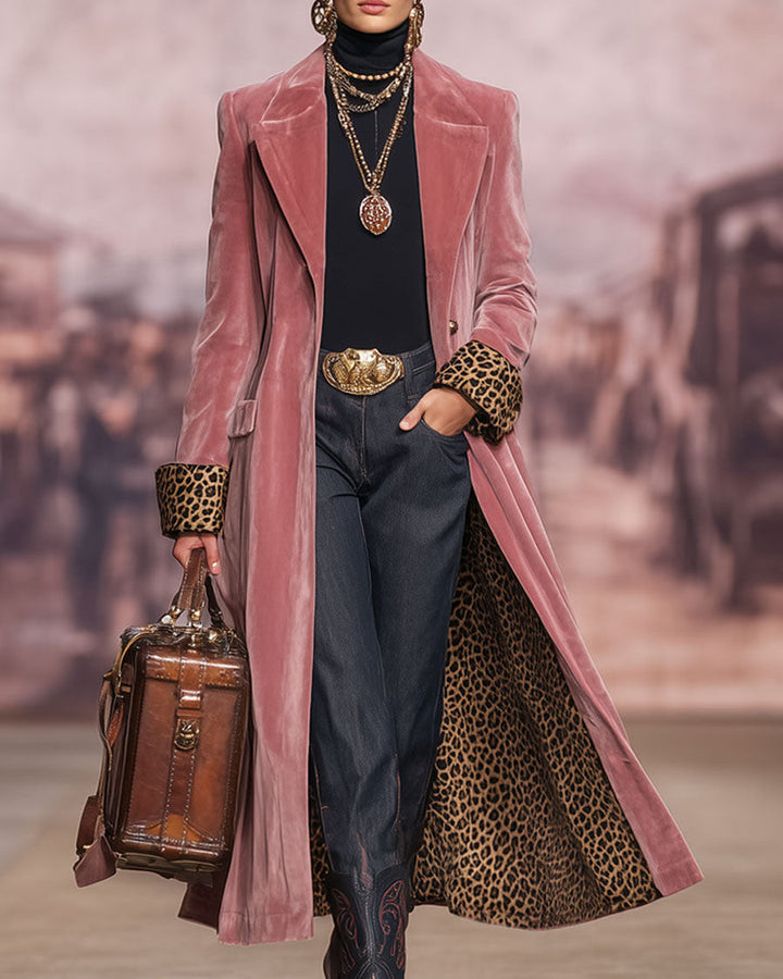 Model op een catwalk draagt de roze fluwelen jas open, met omgeslagen luipaardmanchetten, een hand in de zak en een bruine leren tas. 3