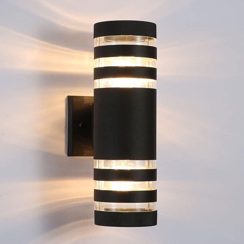 Zwarte cilindrische wandlamp met drie lichtbanden boven en onder, vrijstaand op een effen witte wand gefotografeerd 19
