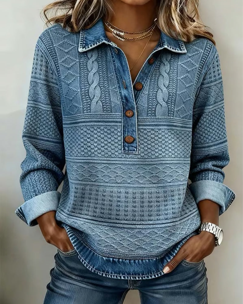 Model draagt de blauwe sweatshirt met kabel- en ruitpatroon, knoopsluiting en denim kraag, handen in de zakken van een spijkerbroek. 1