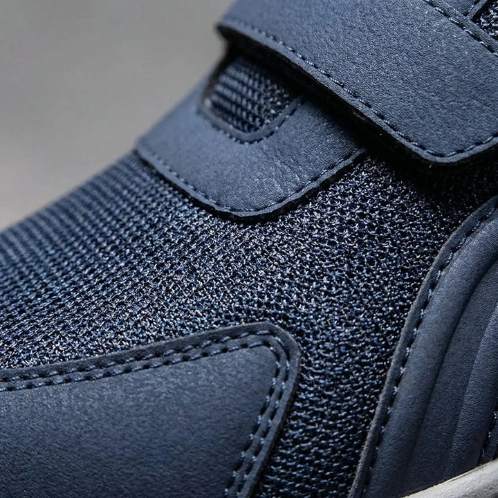 Close-up van het blauwe mesh bovenwerk met gestikte kunstleren neusbescherming en klittenbandriem 10