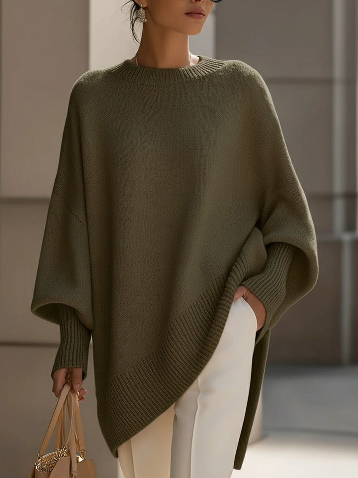 Olijfgroene gebreide poncho gedragen met witte broek en een beige handtas 8