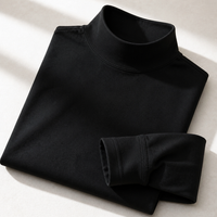 Opgevouwen zwart shirt met close-up van de geribbelde hoge kraag en de gestikte manchet van de mouw. 5