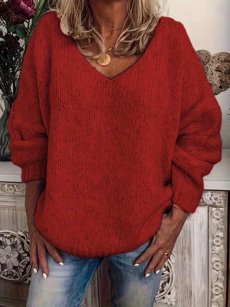 Rode versie van de grofgebreide trui met V-hals, gedragen door een model met gouden ketting en spijkerbroek. 5